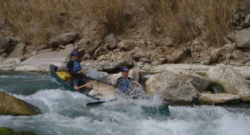 two gap year students paddle a canoe through whitewater on an outward bound expedition in texas